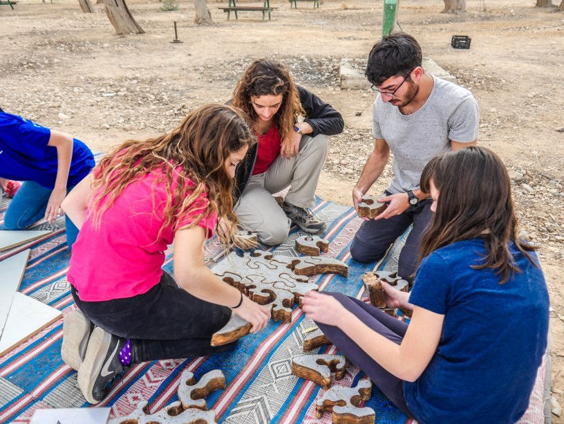 ארבעה בני נוער יושבים על מחצלת בפעילות. קרדיט צלם: תומר שונים